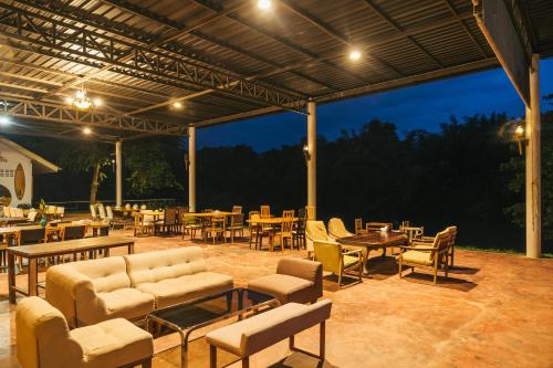 a patio with tables and chairs and tables and tablesktop at Chong khaep aingkwai resort Saiyok in Sai Yok
