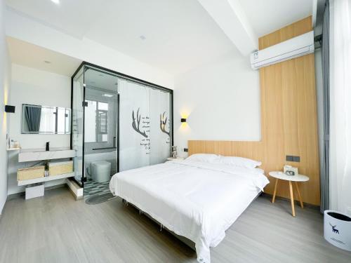 a bedroom with a large white bed and a glass wall at Yunzhan hotel in Dali