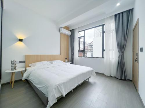 a bedroom with a large white bed and a window at Yunzhan hotel in Dali