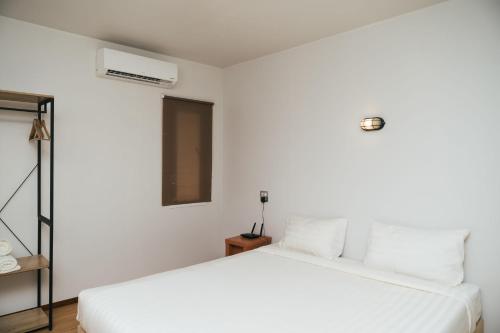 a white bedroom with a bed and a air conditioner at Chong khaep aingkwai resort Saiyok in Sai Yok