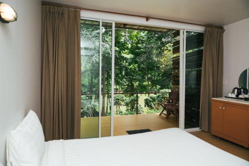 a bedroom with a bed and a large glass window at Chong khaep aingkwai resort Saiyok in Sai Yok