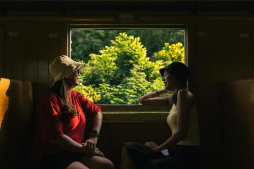 two women sitting in a train looking out a window at Chong khaep aingkwai resort Saiyok in Sai Yok