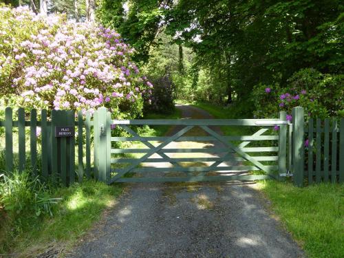 una puerta en un camino con flores rosas en Plas Heulog Holiday Accommodation, en Llanfairfechan