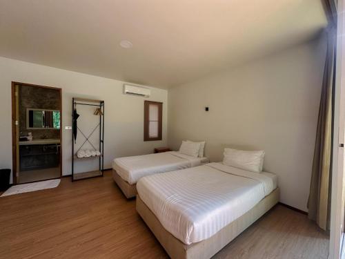 a hotel room with two beds and a mirror at Chong khaep aingkwai resort Saiyok in Sai Yok