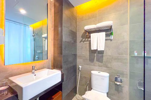 a bathroom with a sink and a toilet and a mirror at Asialink Hotel Batam by Prasanthi in Nagoya