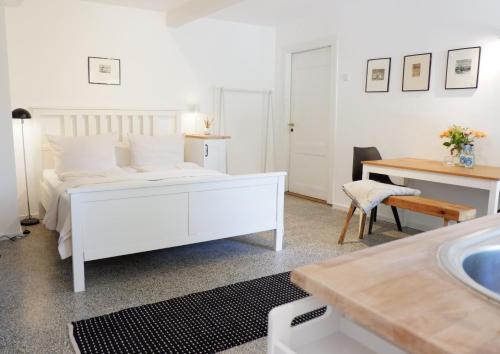 a white bedroom with a white bed and a sink at Appartement Reethus Koppelkiek - kompakt & gemütlich mit Terrasse in Husby