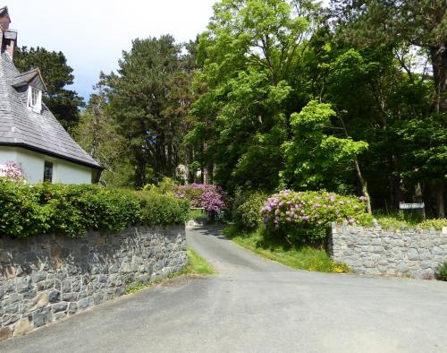 a road next to a stone wall and a house at Plas Heulog Holiday Accommodation in Llanfairfechan