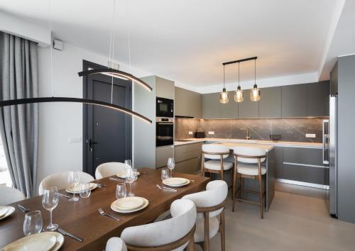 a kitchen with a wooden table and white chairs at Azzura villas in Vasiliki