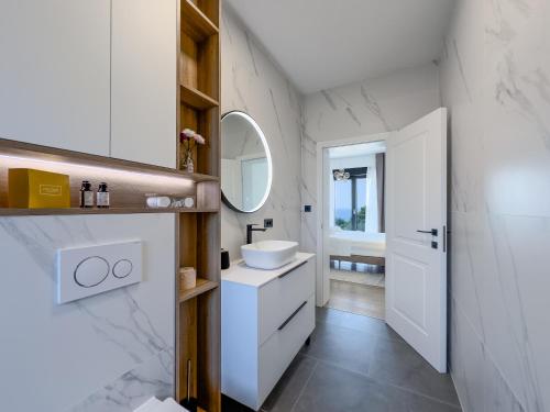 a white bathroom with a sink and a mirror at Villa Allure Lun in Lun