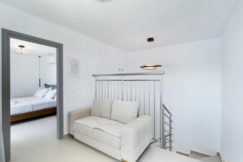 a white room with a chair and a mirror at Azzura villas in Vasiliki