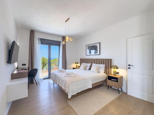 a bedroom with a large white bed and a television at Villa Allure Lun in Lun