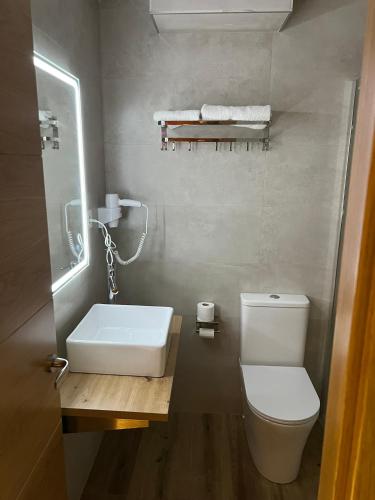 a bathroom with a white toilet and a sink at Hotel Buenos Aires in Villafría de Burgos