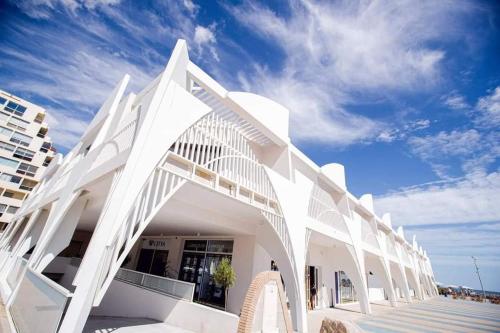 un bâtiment blanc sur la plage avec un ciel bleu dans l'établissement Vacances à la mer, à La Grande Motte