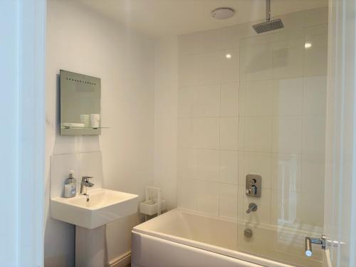 a white bathroom with a sink and a tub and a shower at Sunrise Cottage with on-site swimming and sauna in Filey