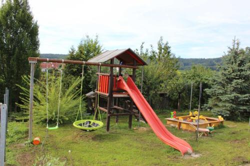 a playground with a red slide and a table at Gaestehaus Zum Wolffenturm in Lehrensteinsfeld