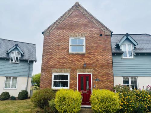 a red brick house with a red door at Sunrise Cottage with on-site swimming and sauna in Filey