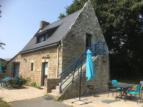 a stone building with a table and a blue umbrella at GITE Le BELLEVUE 2-4 pers, piscine, billiard et baby-foot in Sainte-Hélène