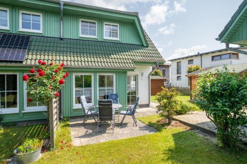 a green house with a table and chairs in the yard at Ferienhaus Knospe in Ueckeritz