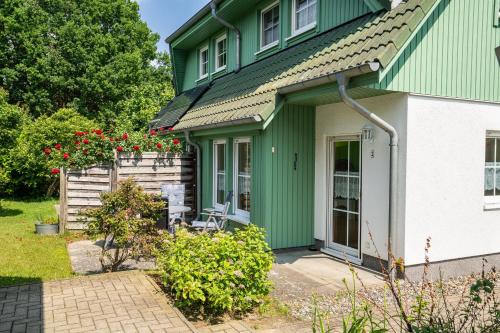a green and white house with a patio at Ferienhaus Knospe in Ueckeritz