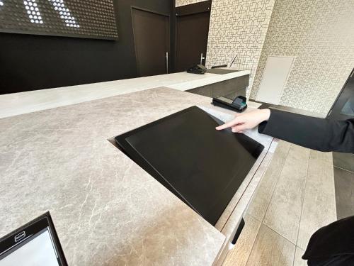 a hand pointing at a tablet on a counter at Green Rich Hotel Matsue Station Across - Artificial hot spring Futamata Yunohana in Matsue