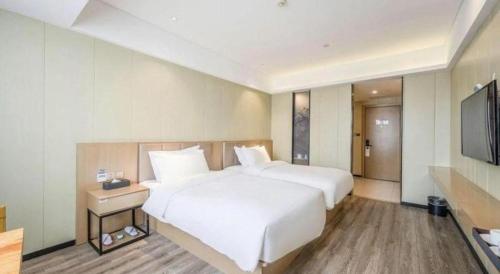 a bedroom with a large white bed and a flat screen tv at Borrman Hotel Xiamen Xiang'an Maxiang in Xiamen