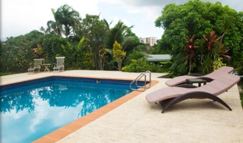 a swimming pool with a bench and a table and chairs at Five Princes Hotel in Suva