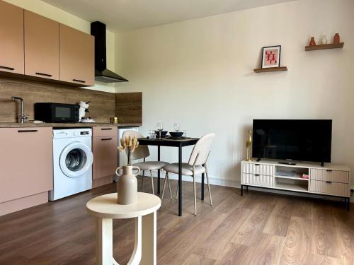 a kitchen with a table and a washing machine at L'instant Villersois, Paisible et Idéalement situé in Villers-sur-Mer