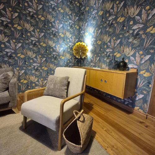 a living room with a chair and floral wallpaper at Ferienwohnung "Mittendrin" in Neubrandenburg