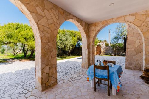 a stone archway with a table and chairs in a patio at L`Oasi del Mare by BarbarHouse in Torre rinalda