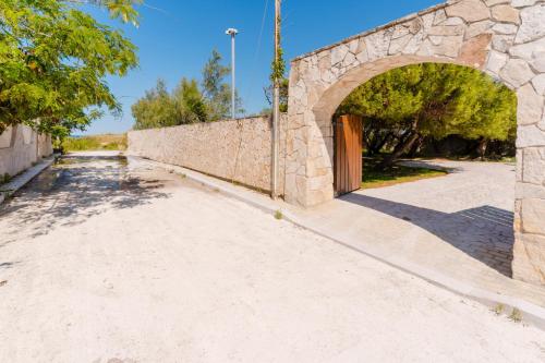 a stone wall with an archway next to a road at L`Oasi del Mare by BarbarHouse in Torre rinalda