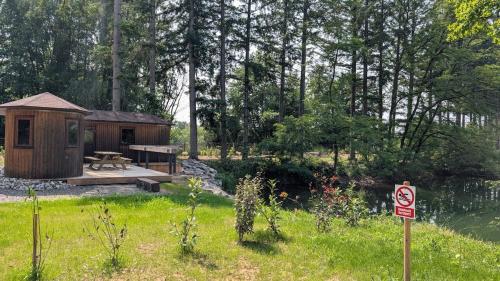 a wooden cabin with a picnic table next to a pond at L'Écorce & le Tanin - 2 cabanes cosy pour 4, pêche in Roye