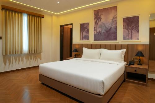 a bedroom with a large white bed and a window at Hotel Royal King in Ahmedabad