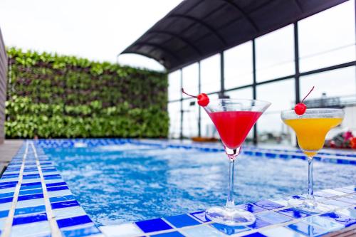 two cocktails on a table next to a swimming pool at Shining Central Hotel & Spa in Hanoi