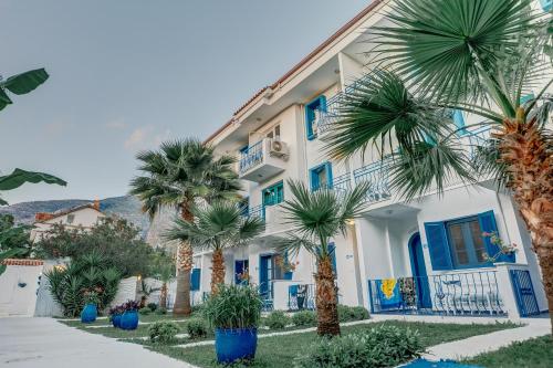 a white building with blue doors and palm trees at Monta Verde Hotel & Villas in Oludeniz