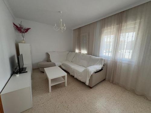 Una sala de estar con un sofá blanco y una mesa. en Casa Rubio, en Chiclana de la Frontera