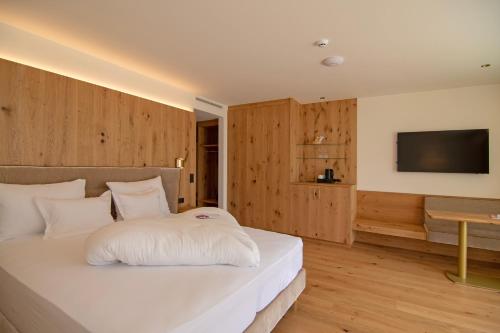 a bedroom with a white bed with a television on the wall at Hotel Nocturnes in Naturno