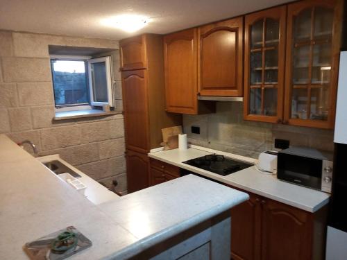 a kitchen with wooden cabinets and a counter top at Fishing Family House in Čilipi