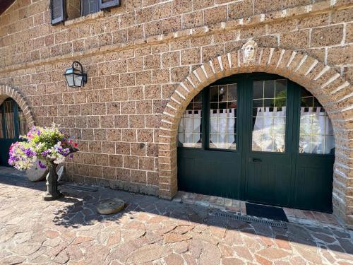 a brick building with a green door and a vase of flowers at B&b La Baronata - Pescosansonesco (Pe) in Pescosansonesco
