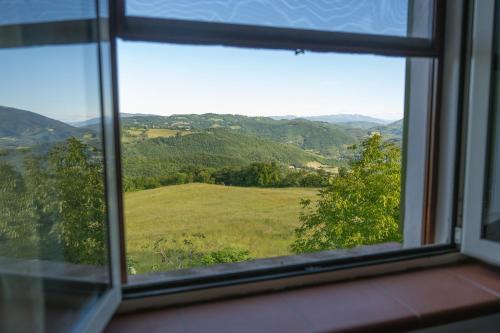 a window with a view of a field and mountains at Agriturismo Casa del Vento in San Presto