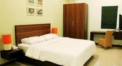 a bedroom with a large white bed and a desk at The Studio Inn Nusa Dua in Ubud