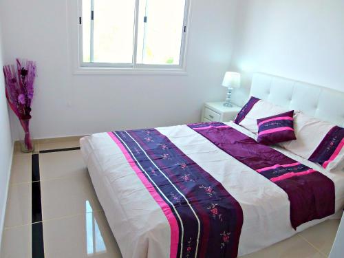 ein Schlafzimmer mit einem Bett mit einer lila und weißen Decke in der Unterkunft Coral Bay Apartment - Prime Tourist Location in Coral Bay
