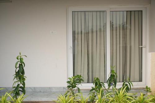 a white house with a window with plants in front of it at Simbaa Resorts and Conventions 