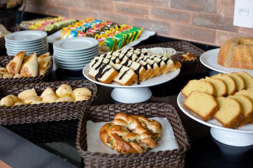 a table topped with plates of bread and pastries at Hotel Pousada do Bosque in Ponta Porã