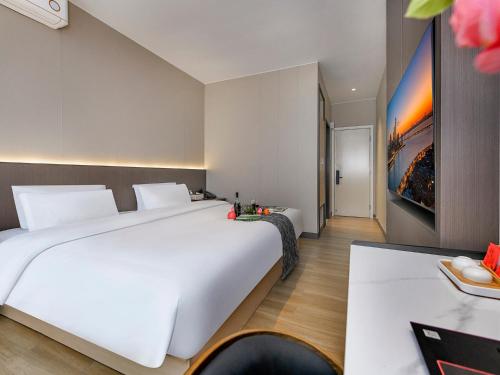 a bedroom with a large white bed and a table at 重庆莎霏酒店大渡口店 in Chongqing