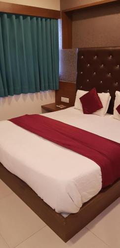 a bedroom with a large bed with red and white sheets at Hotel Royal King in Ahmedabad