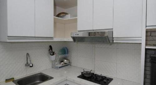 a kitchen with white cabinets and a sink at OYO Living 3091 Apt The Suites Metro By Ananda in Bandung