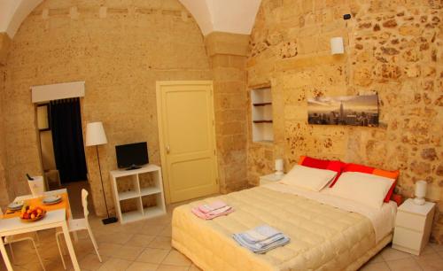 レッチェにあるCasa Fortunato Corte Adorniの石壁のベッドルーム1室