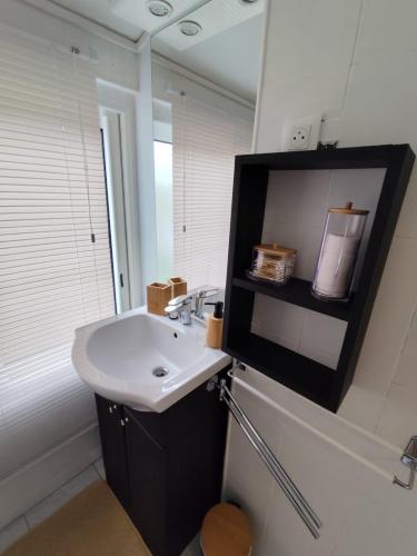 une salle de bain avec un lavabo et une télévision au mur dans l'établissement Pouzet 1, à Saujon