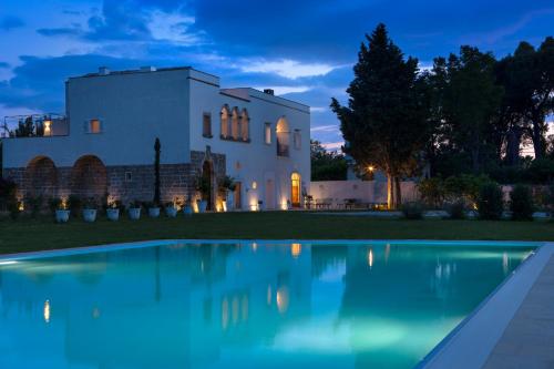 une villa avec une piscine la nuit dans l'établissement Critabianca - Masseria in Salento, à Cutrofiano