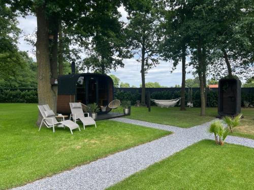 a garden with a hammock and chairs and a tree at Maison Idyllique in Bree
